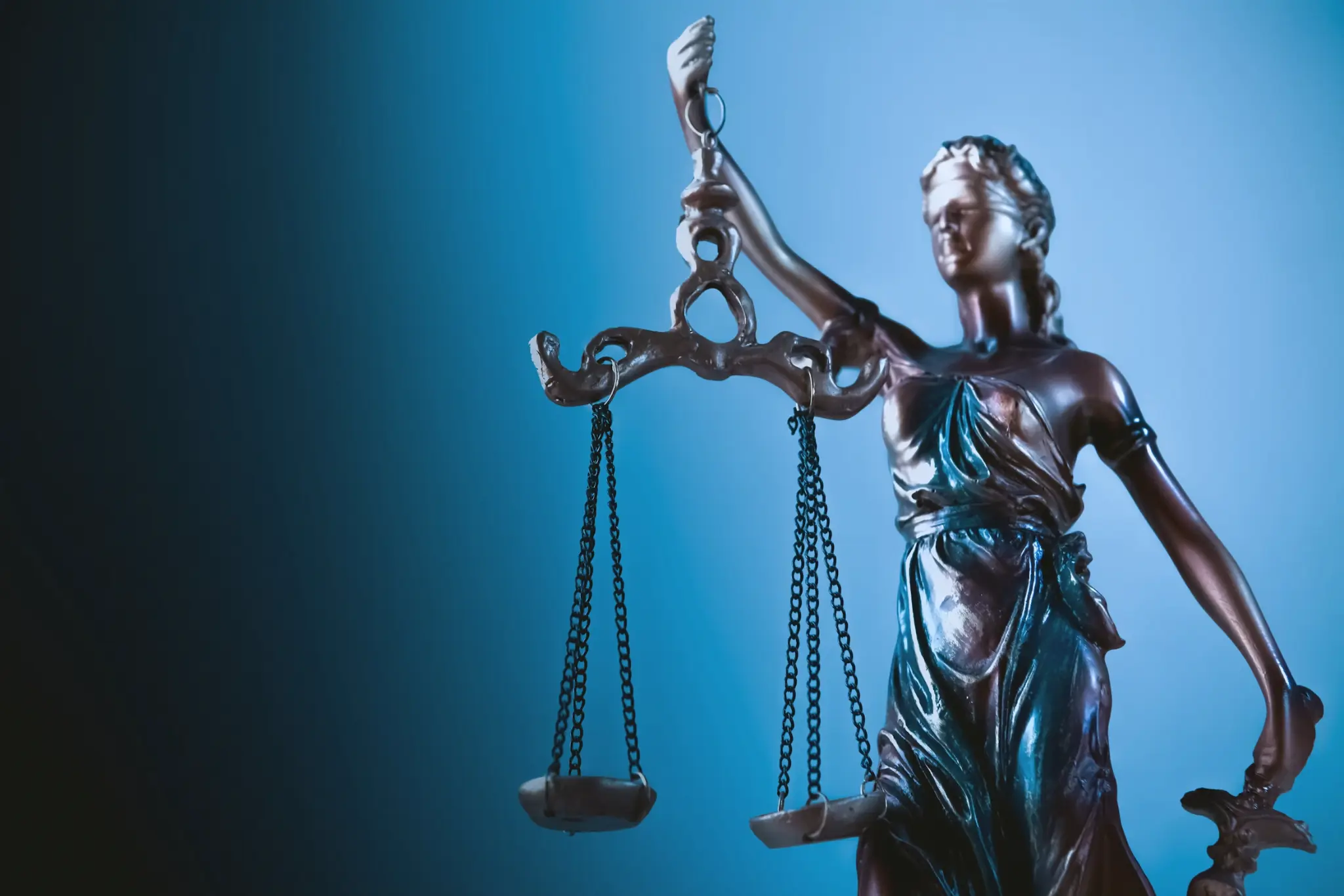 A balance of justice statue against a blue background.
